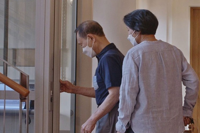 khun charn and his wife entering the elderly lift